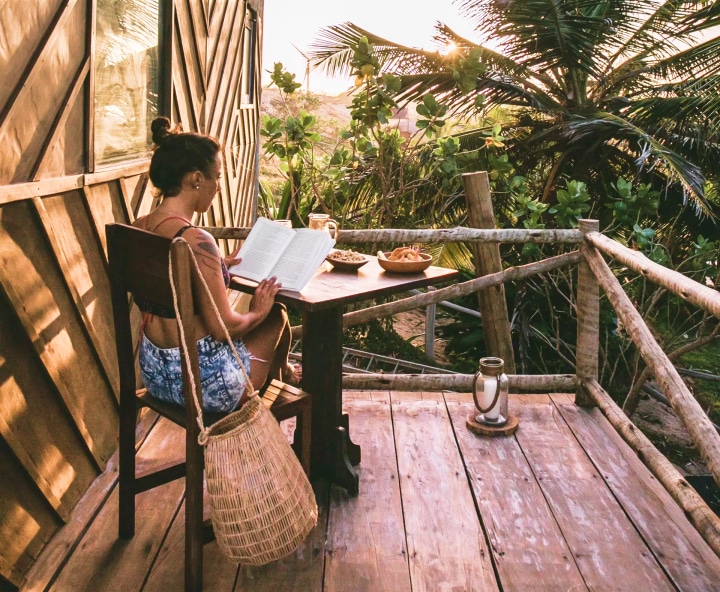 Villa Mango lendo livro no deck com vista para o mar
